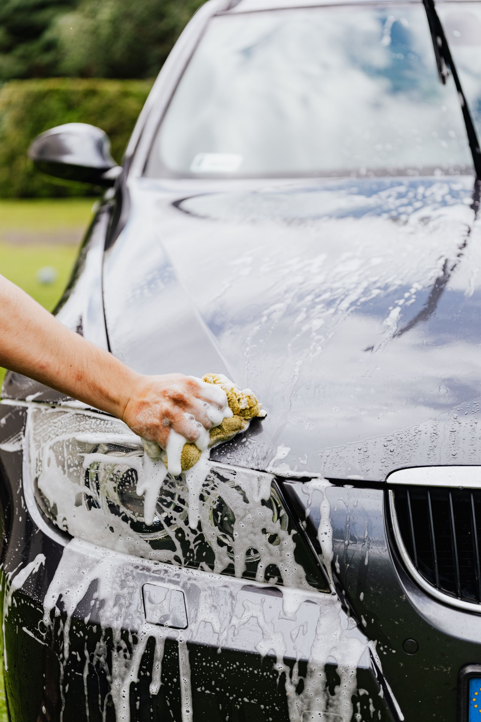 A detailer washing a car by hand with a wash mitt